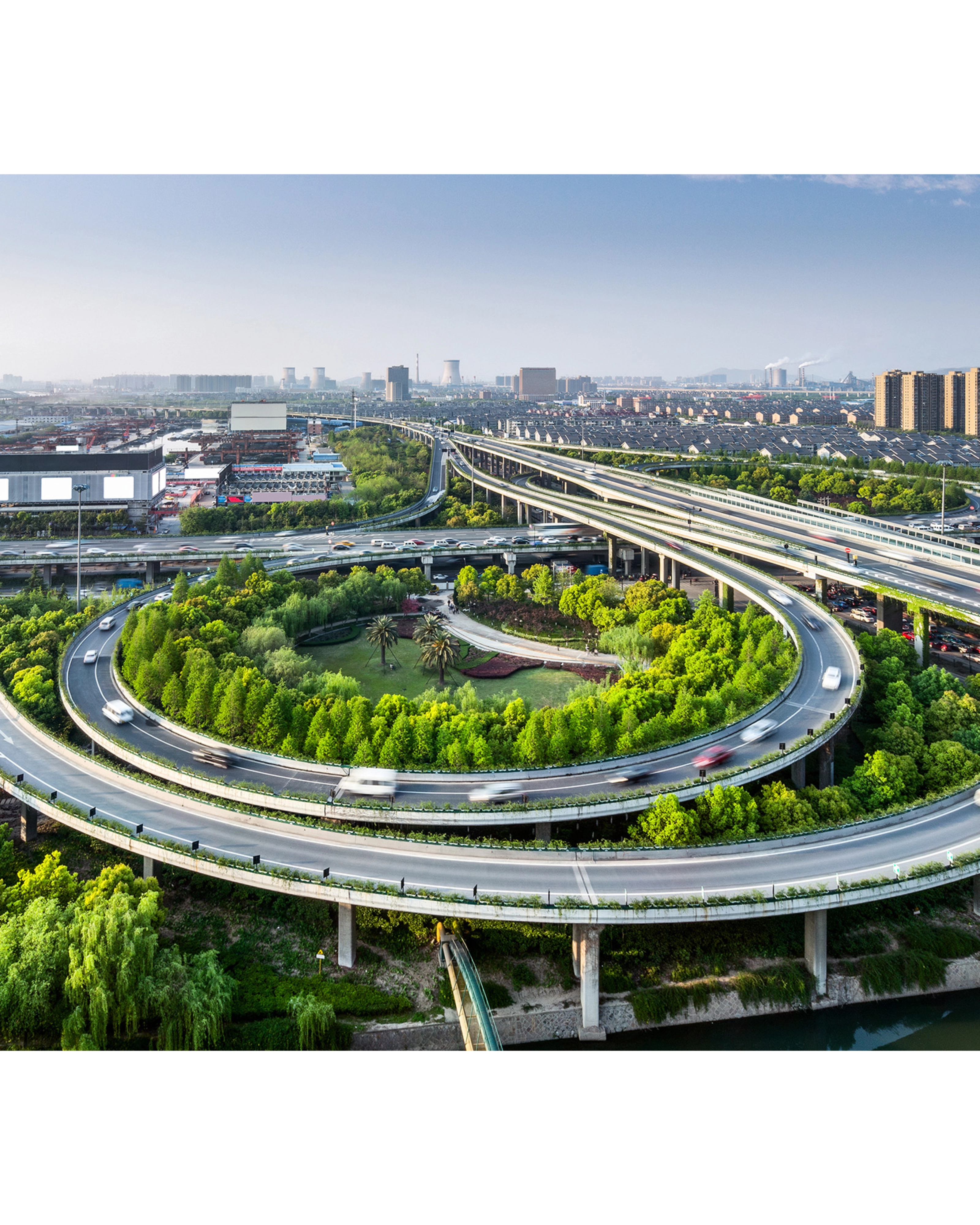 Large highway interchange with loop ramps and green areas in an urban cityscape.